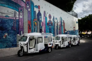 Tres tuk tuks aparcados frente a un muro de colores