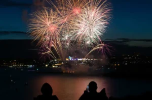 Two people watching fireworks over a river