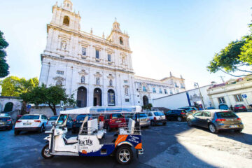 Several vehicles, including a tuk tuk, parked in front of Sao Vicente de Fora Monastery in Lisbon