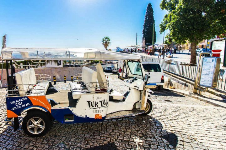 Empty tuk tuk parked in a busy viewpoint in Lisbon