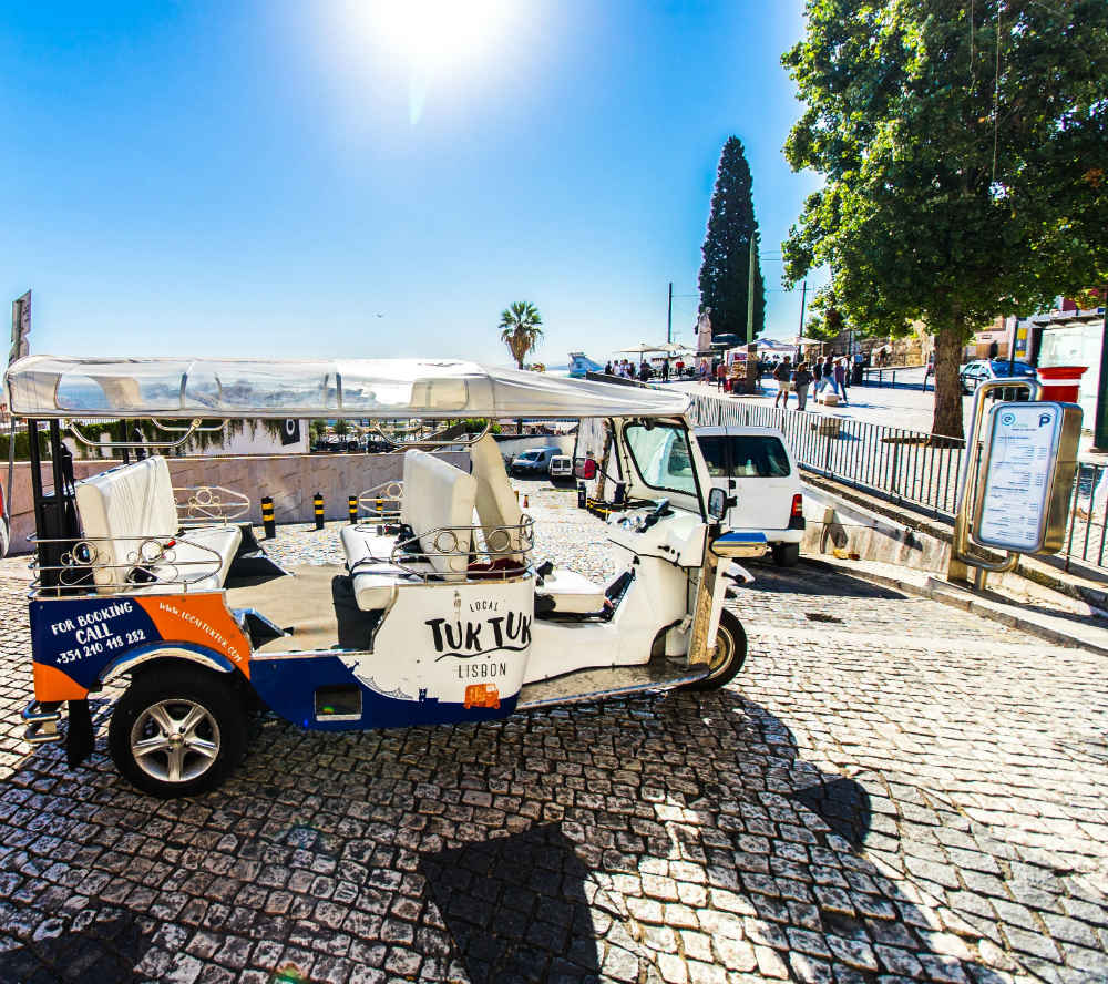 Tuk tuk vazio estacionado num miradouro movimentado em Lisboa