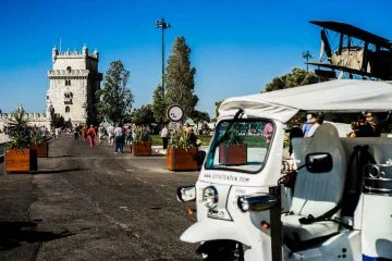 Side of a white tuk tuk with the belem tower in the background