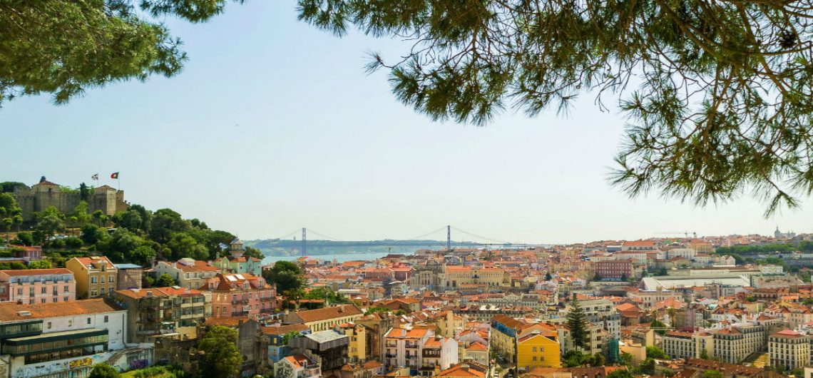View from in between pine trees of Lisbon's buildings and the Saint Jorge Castle