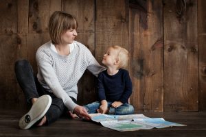 Madre sentada en el suelo con su niño mientras sostiene un mapa