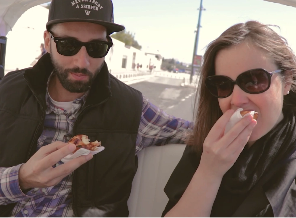 Two people inside a tuk tuk eating custard tarts
