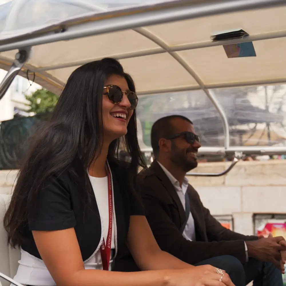 Two people laughing while sitting inside a tuk tuk